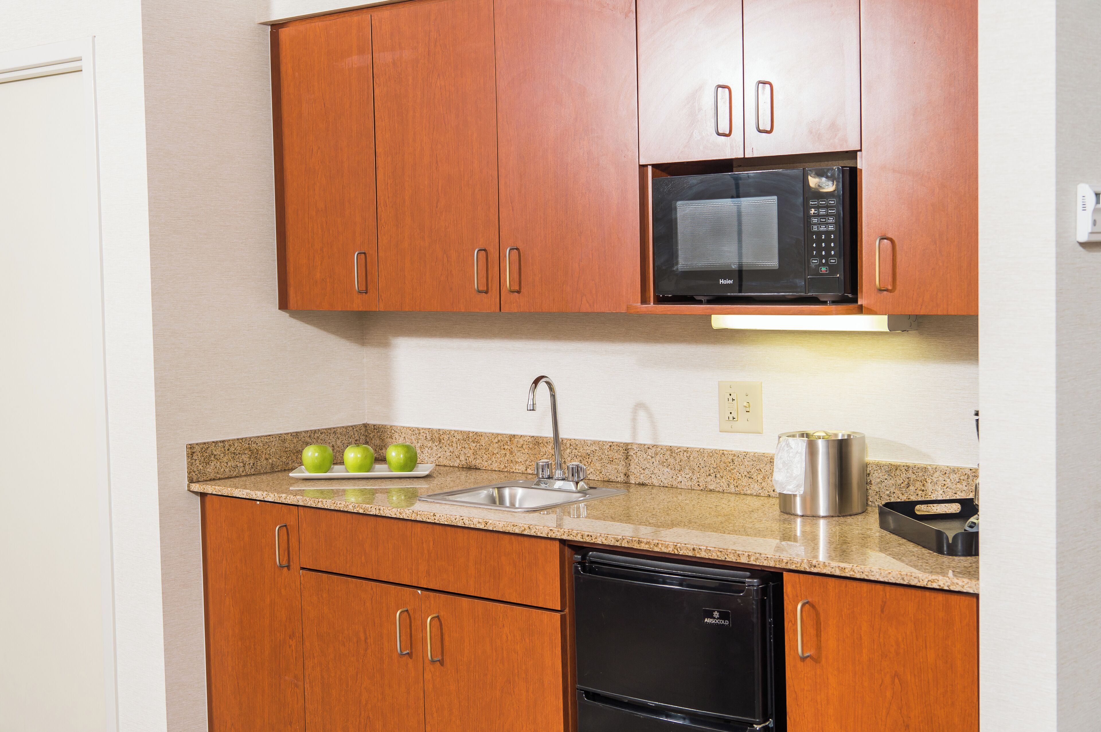 A kitchen with wooden cabinets, a stainless steel sink, a microwave, and a dishwasher.