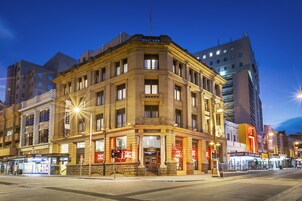 A historic building with a corner entrance, multiple stories, and a prominent sign.