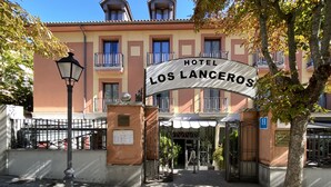 La entrada del Hotel Los Lanceros, con un cartel claro, un acceso con portón y un farol.
