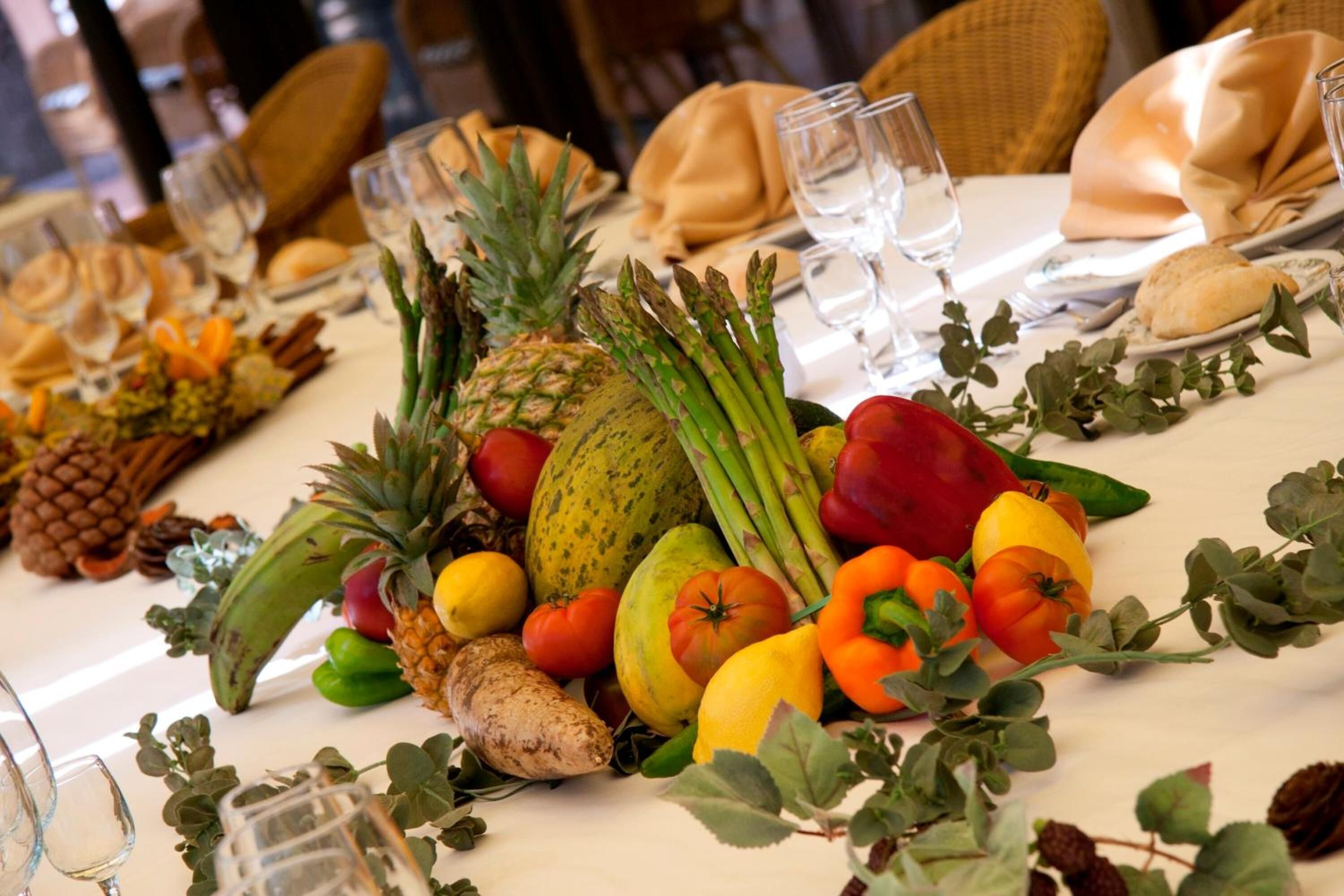 Una mesa dispuesta para una comida, con diversas frutas y verduras, incluyendo piña, espárragos y tomates.