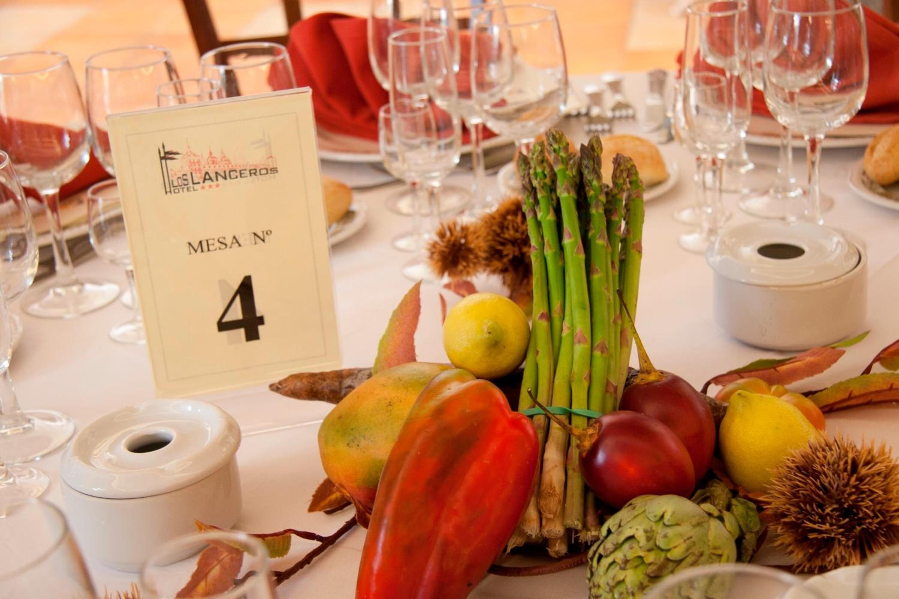 A table set for a meal with a variety of fresh vegetables, a number sign indicating table 4, and wine glasses and plates.