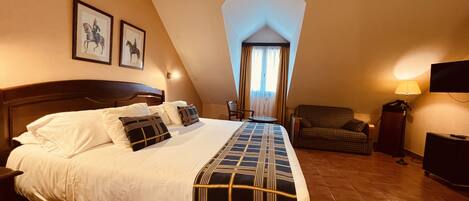 Una habitación de hotel con una cama grande, una silla, un televisor y una lámpara.