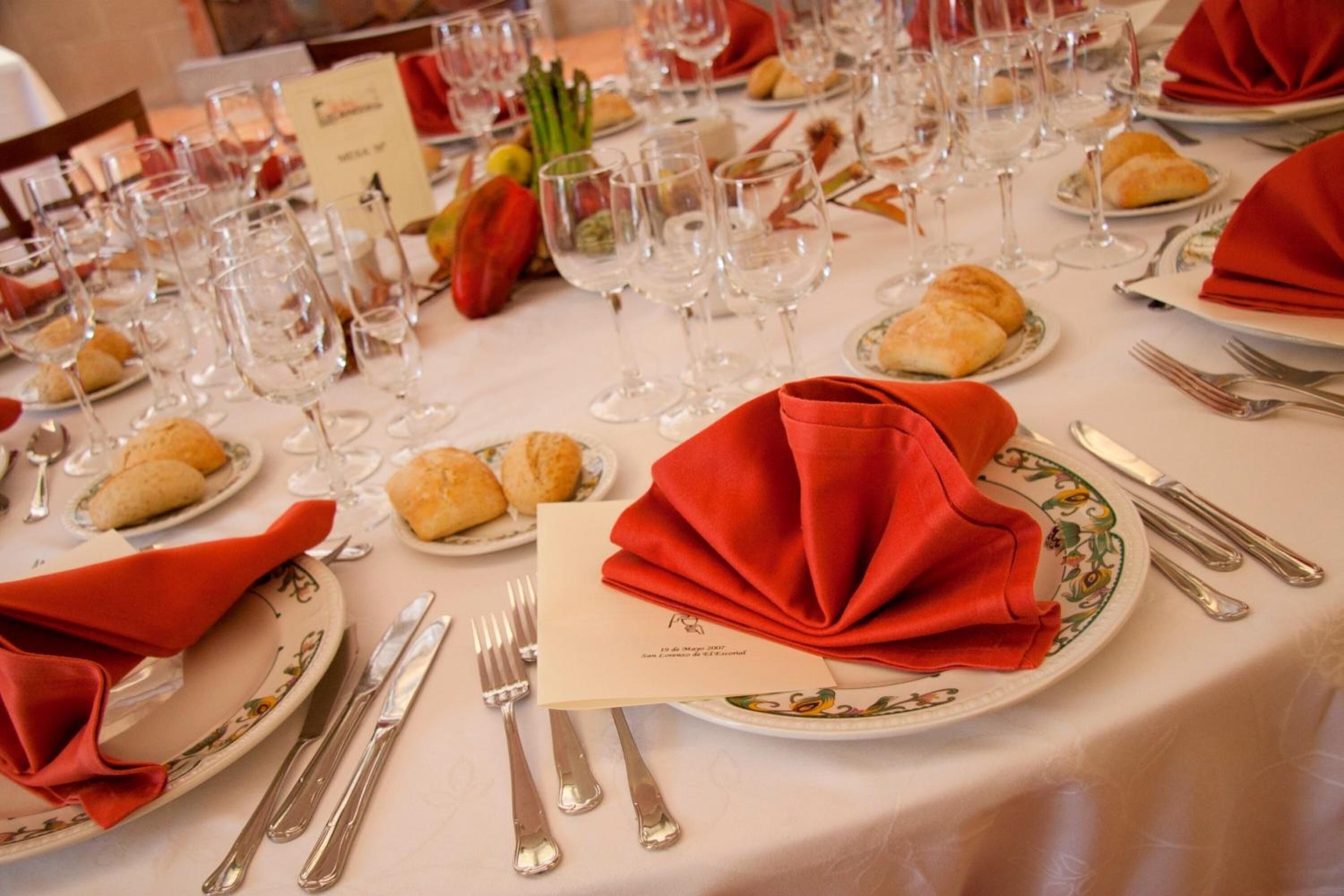 A formal dining table set with multiple plates, glasses, and cutlery, indicating a restaurant or banquet setting.