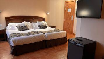A hotel room with two beds, a TV, and a small cabinet.