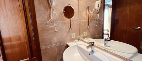 Un baño con dos lavamanos, un espejo y un secador de pelo montado en la pared.