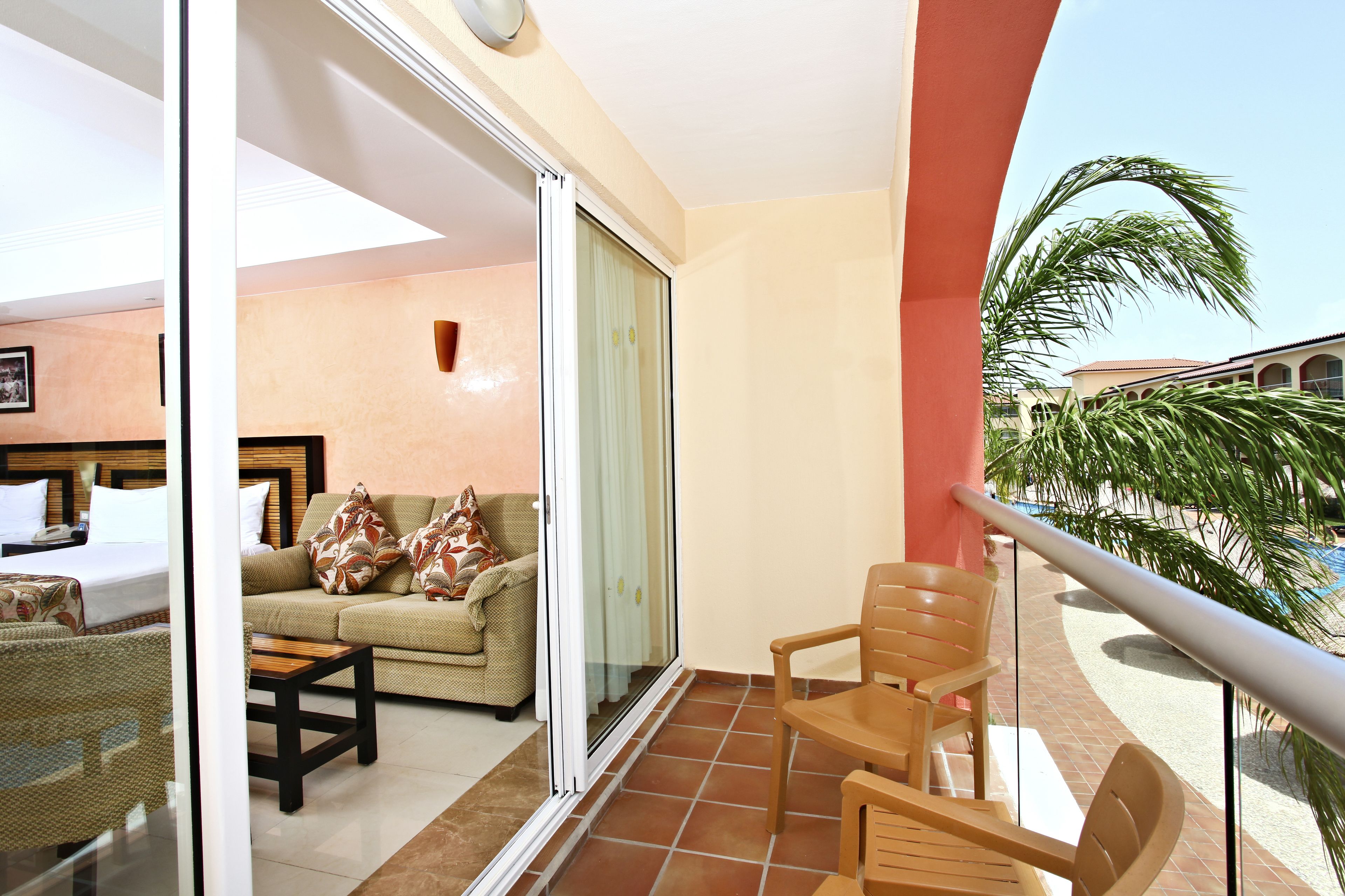 A balcony with a sliding glass door leading to a living area with a sofa and chairs.