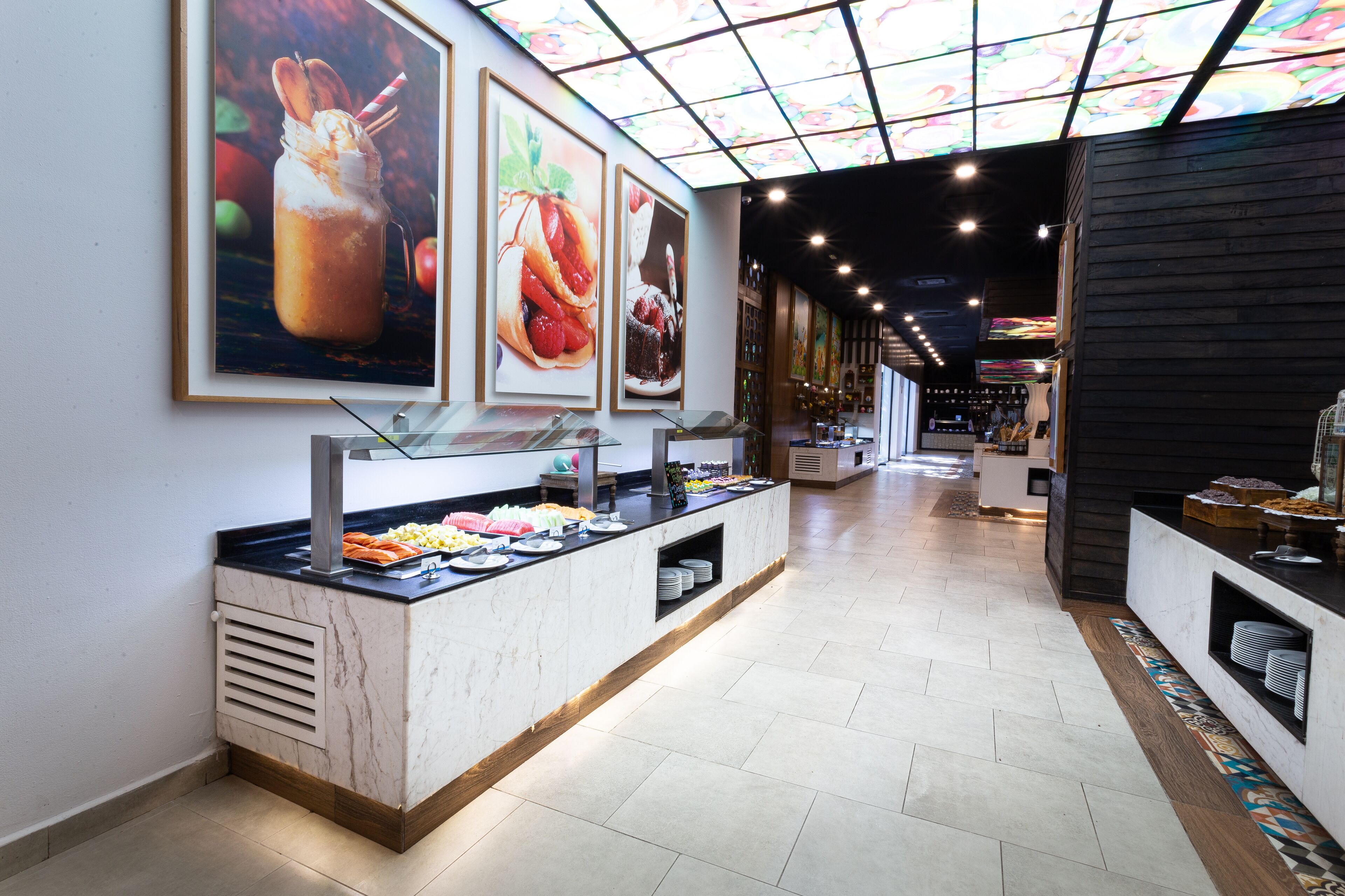 A buffet area with a marble counter, food displays, and a ceiling with a stained glass design.