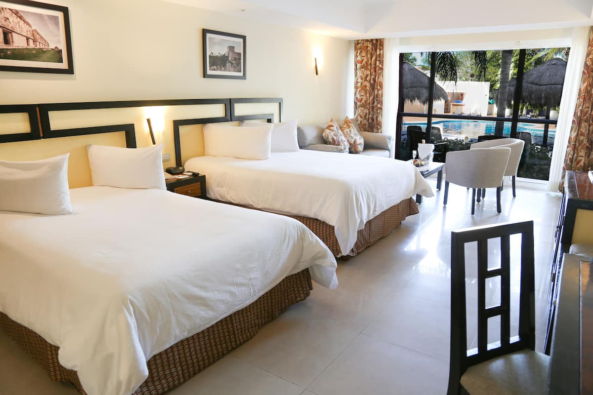 Une chambre d’hôtel avec deux lits, un coin repas et une vue sur une piscine.