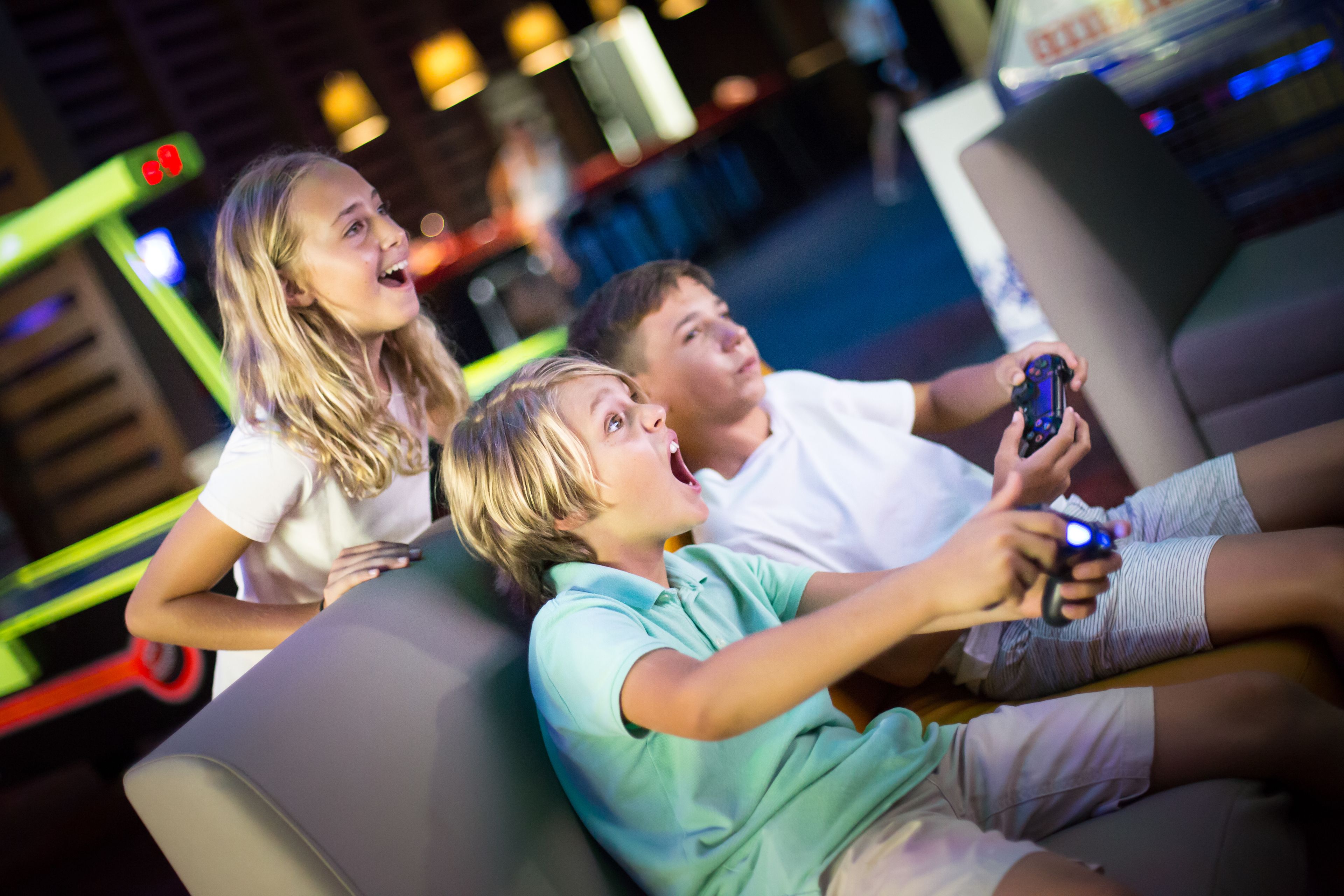 Three people sitting on a couch, one holding a game controller.