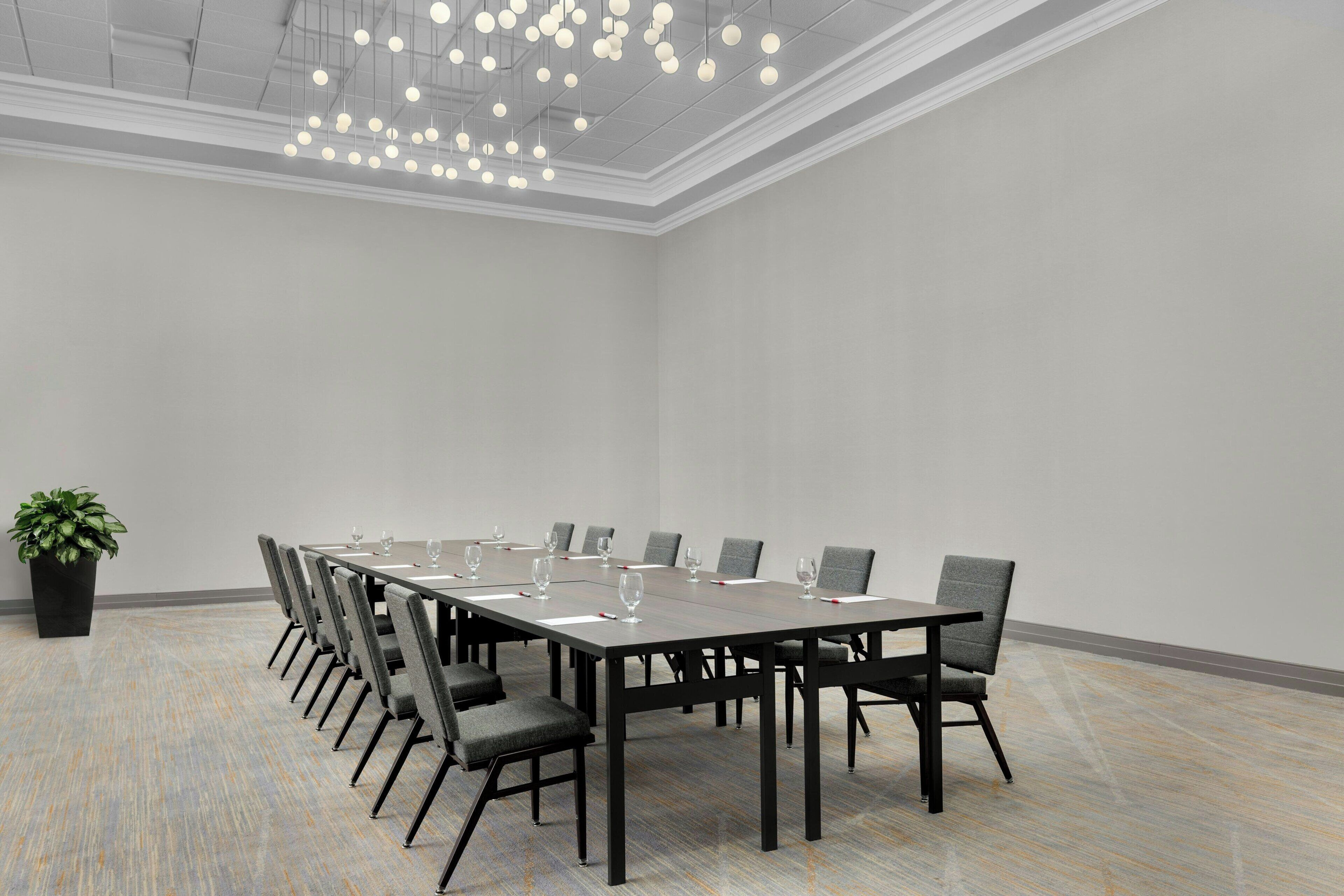 A conference room with a long table, chairs, and a hanging light fixture.