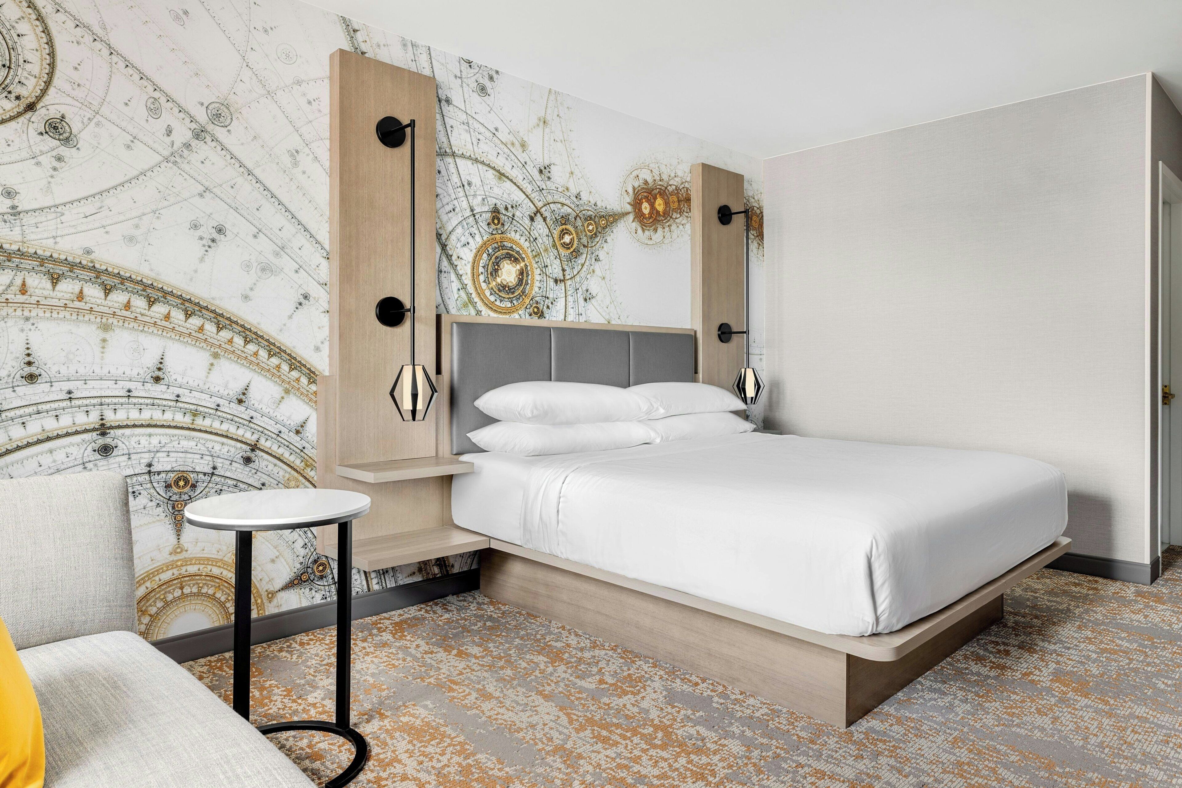 A modern bedroom with a bed, a round side table, and a wall with a decorative map.