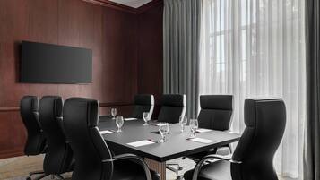 A conference room with a large table, black chairs, and a flat-screen TV on the wall.