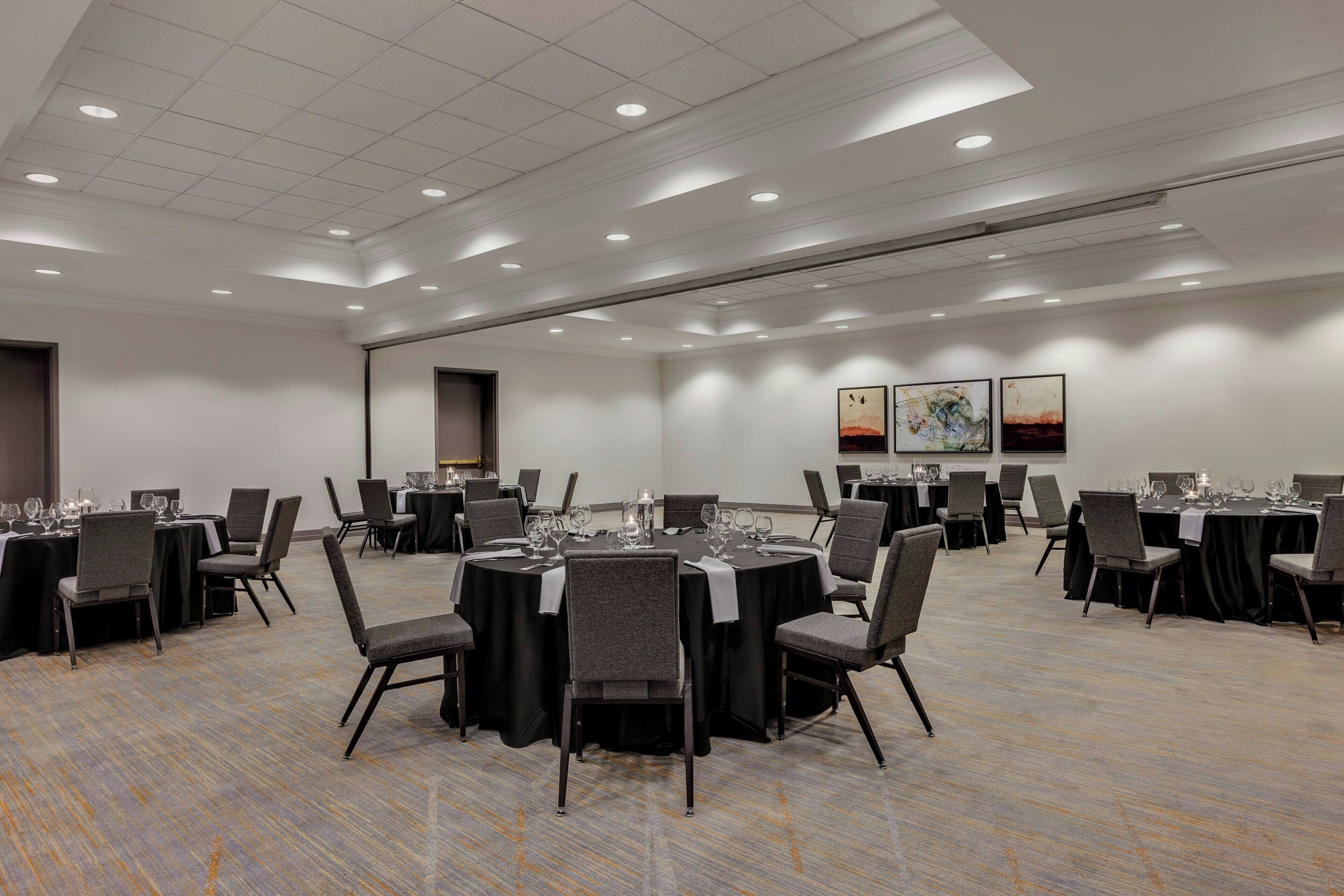 A conference room with round tables, chairs, and a carpeted floor.