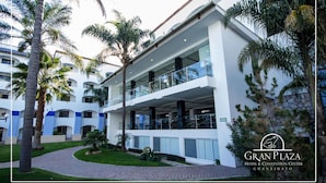 A hotel with a modern design, featuring multiple balconies and a well-maintained garden with palm trees. - Gran Plaza Hotel & Convention Center (Guanajuato)