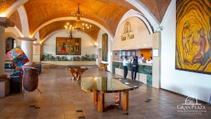 A lobby with a high arched ceiling, a reception desk, and a large painting on the wall. - Gran Plaza Hotel & Convention Center (Guanajuato)