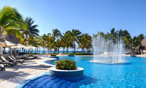 Una piscina al aire libre, sombrillas, sillones reclinables de piscina