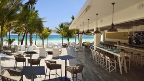 A beachside restaurant with outdoor seating, a bar, and a view of the ocean. - Catalonia Royal Tulum  Adults Only - All Inclusive (Xpu-Ha)