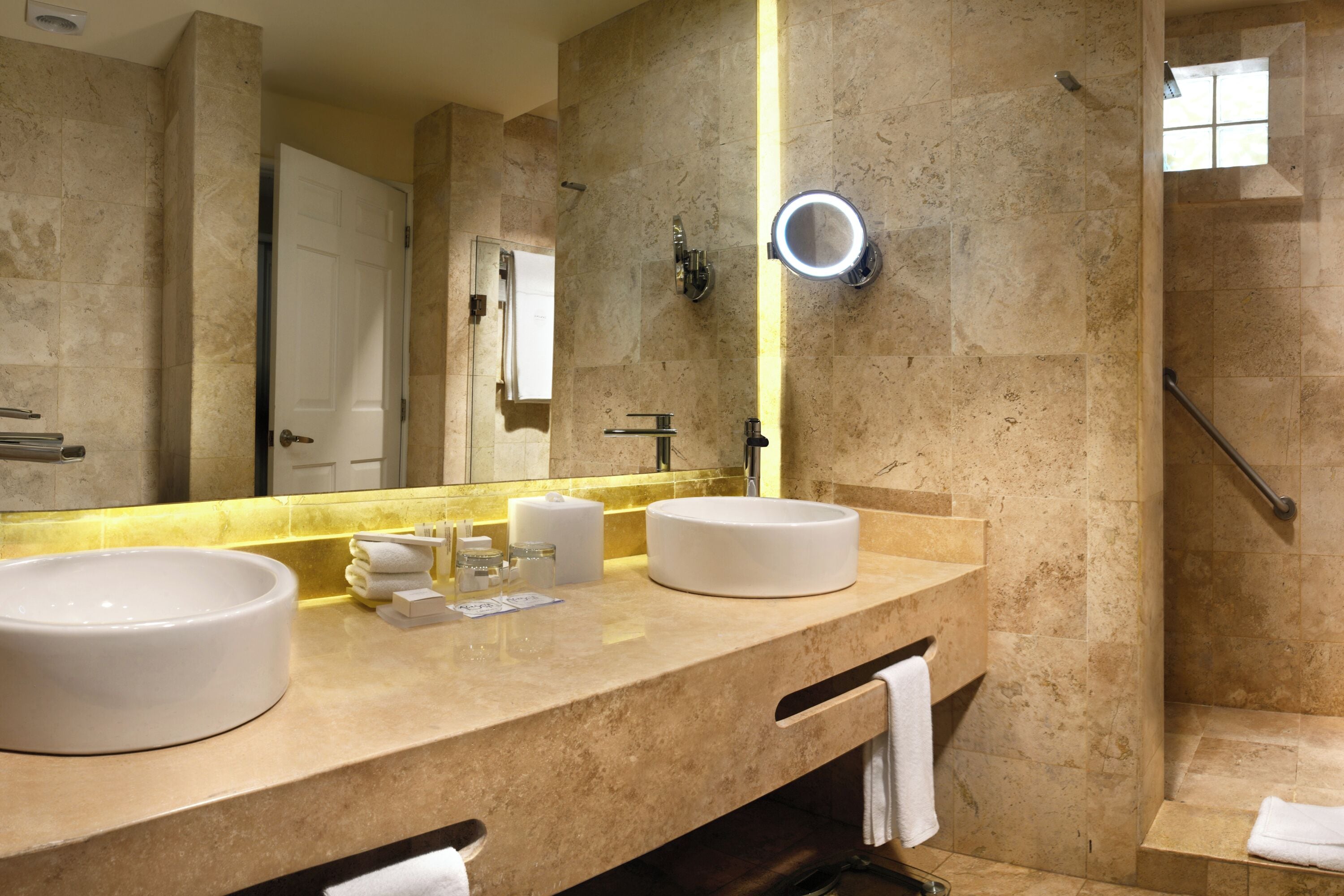 A bathroom with two sinks, a mirror, a towel rack, and a shower area.
