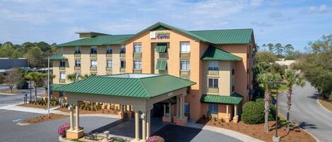 A hotel with a green roof, a covered entrance, and a parking lot.