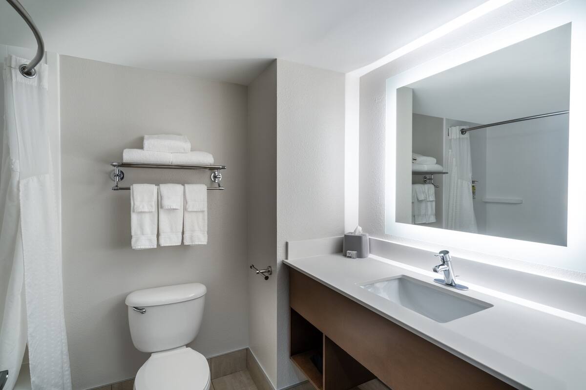 A modern bathroom with a toilet, a sink, and a mirror.