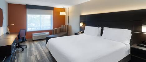 Una habitación de hotel con una cama grande, un escritorio, una silla, una mesita de noche y un ventanal.