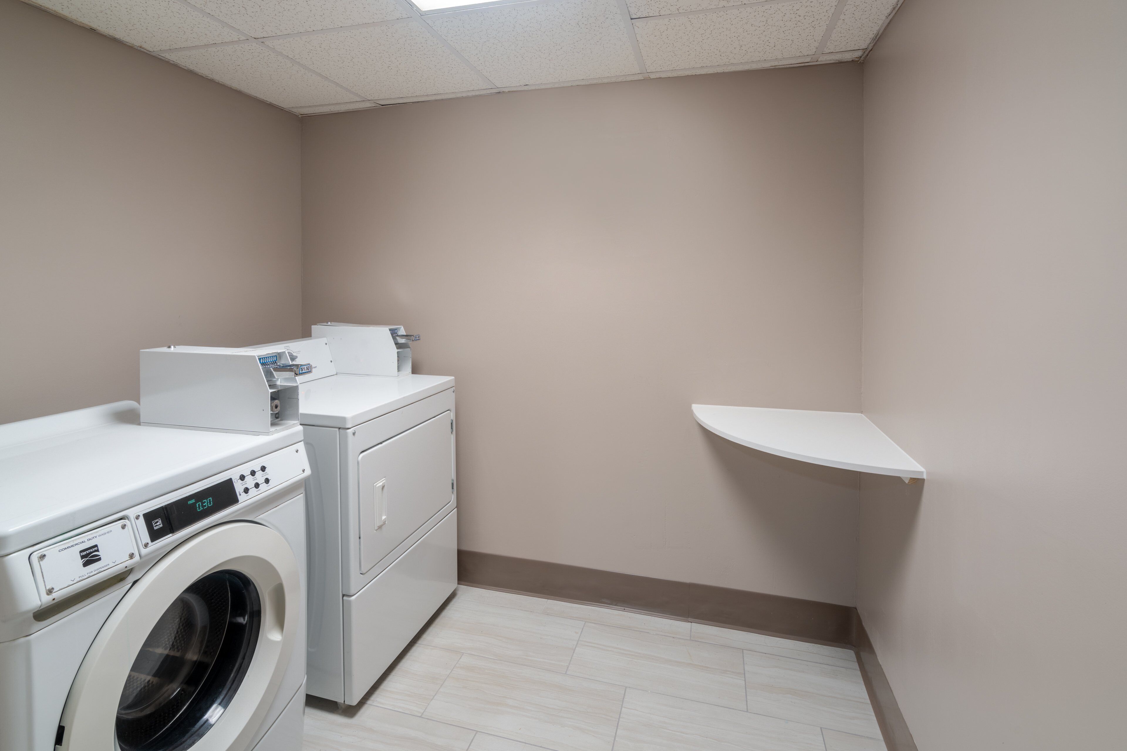 A laundry room with a washing machine, dryer, and a small shelf.