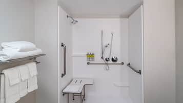 A modern bathroom with a walk-in shower, grab bars, a bench, and a towel rack.