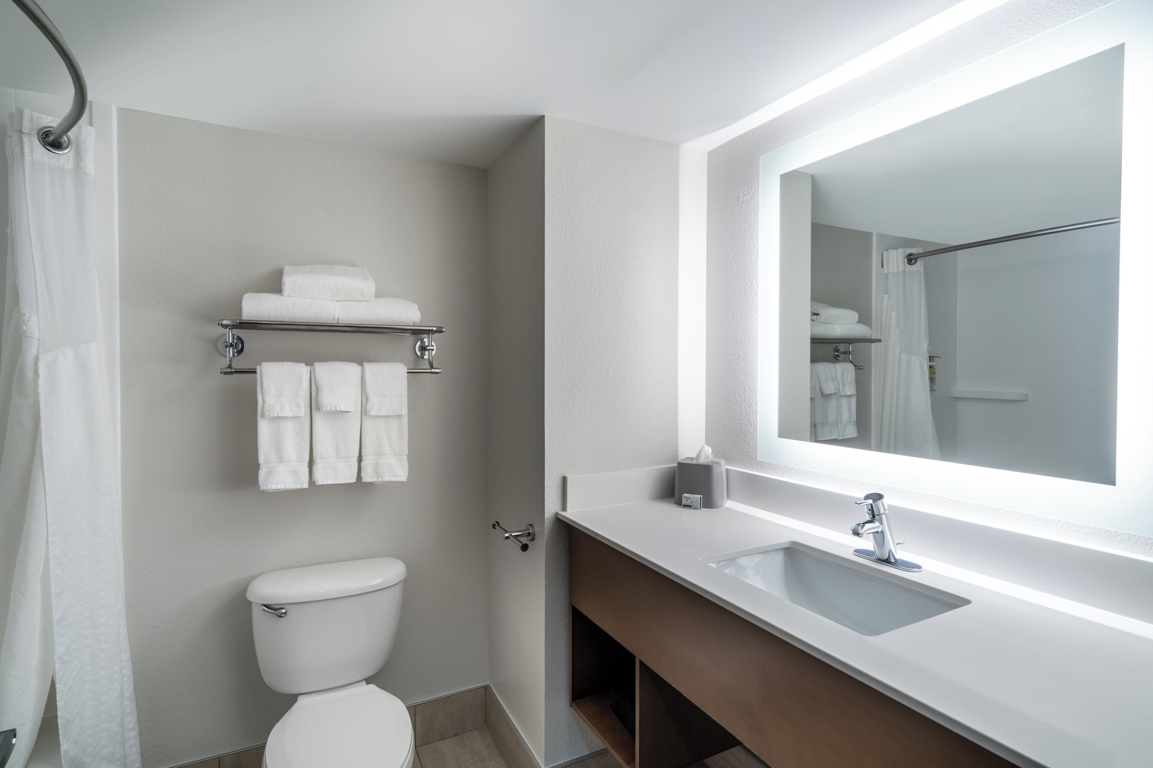 A modern bathroom with a toilet, a sink, a mirror, and a towel rack.