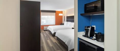 Een hotelkamer met twee bedden, een magnetron, een koffiezetapparaat en een kleine koelkast.