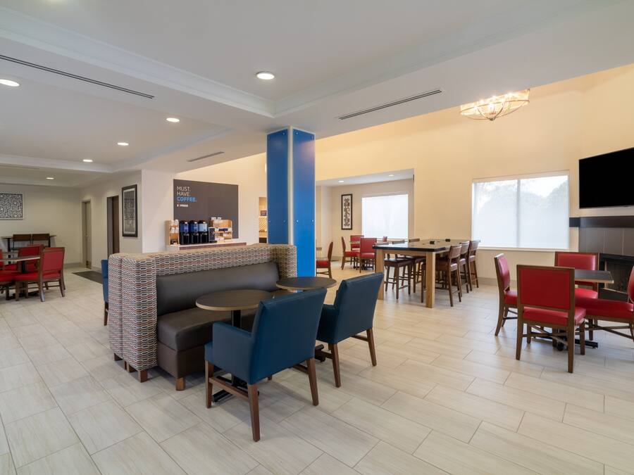 A spacious hotel lobby with a central seating area, a bar, and a television mounted on the wall.