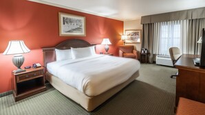 Une chambre d’hôtel avec un grand lit, deux tables de chevet avec des lampes, un bureau, une chaise et un téléviseur.