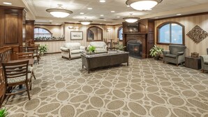 Une pièce spacieuse avec un tapis à motifs, des meubles en bois, une cheminée et de grandes fenêtres.