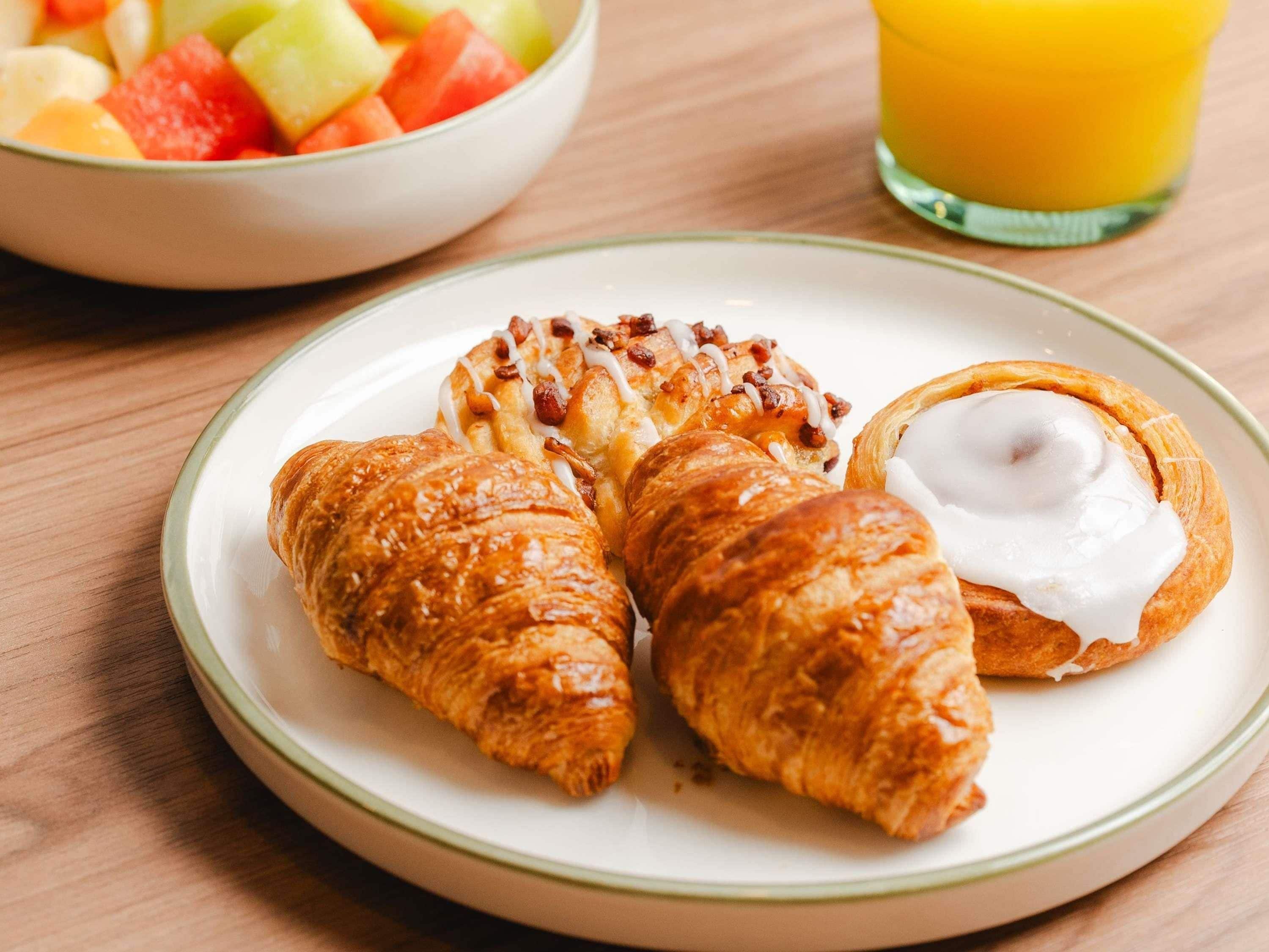 A plate with croissants and a bowl of fruit.