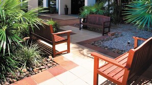 Een binnenplaats met terras, een palmboom en een gebouw met blauwe raamkozijnen.