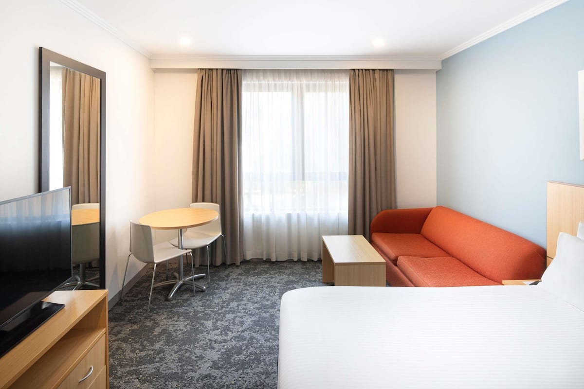 Een hotelkamer met een bed, een televisie, een bureau, een stoel en een bank.