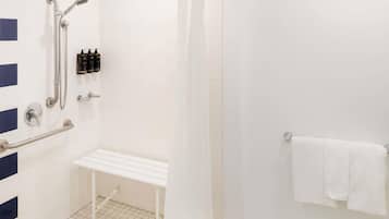 Un baño con ducha, banco, barras de apoyo y un perchero para toallas.