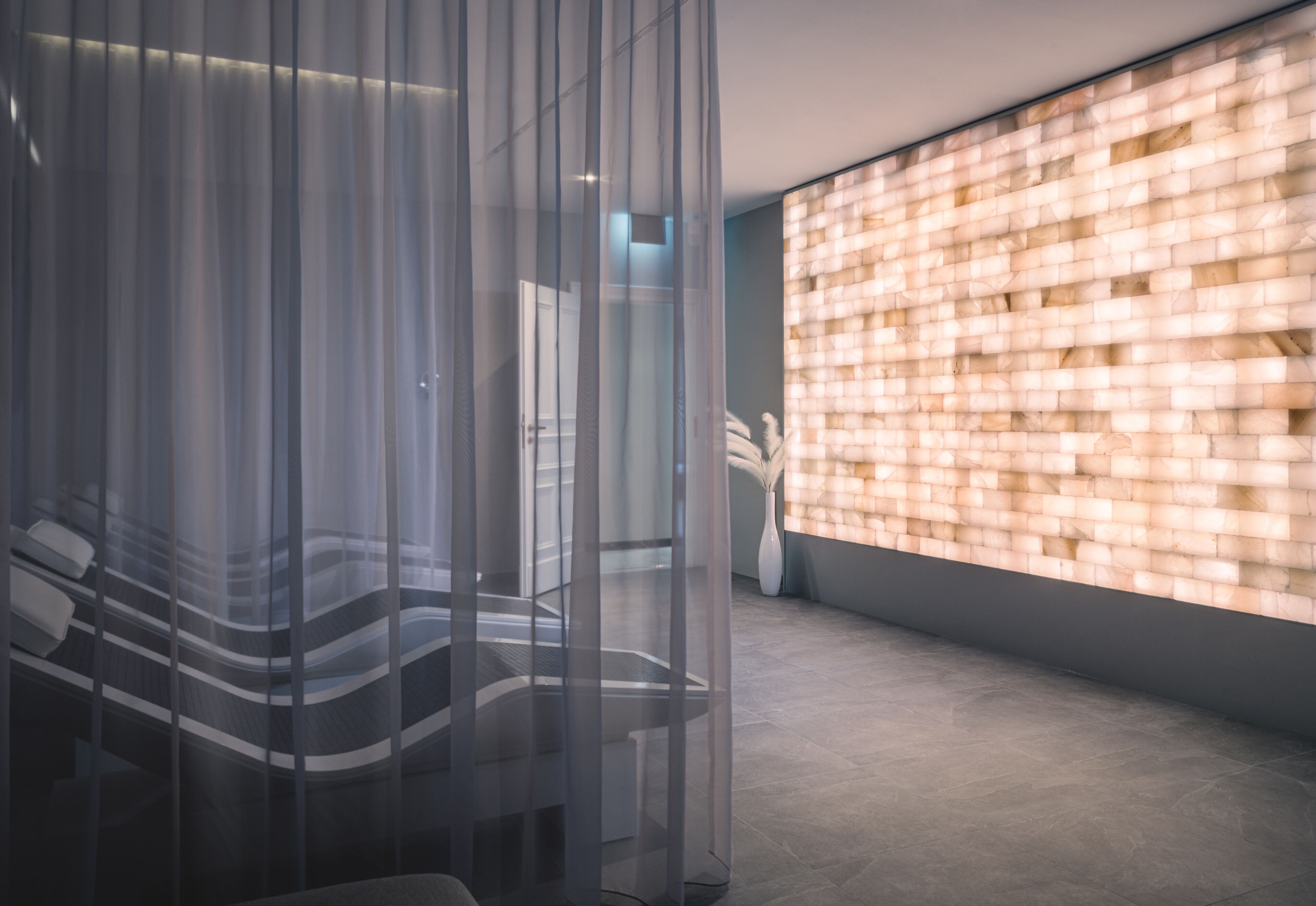 A modern interior with a glass partition, a brick-patterned wall, and a tiled floor.