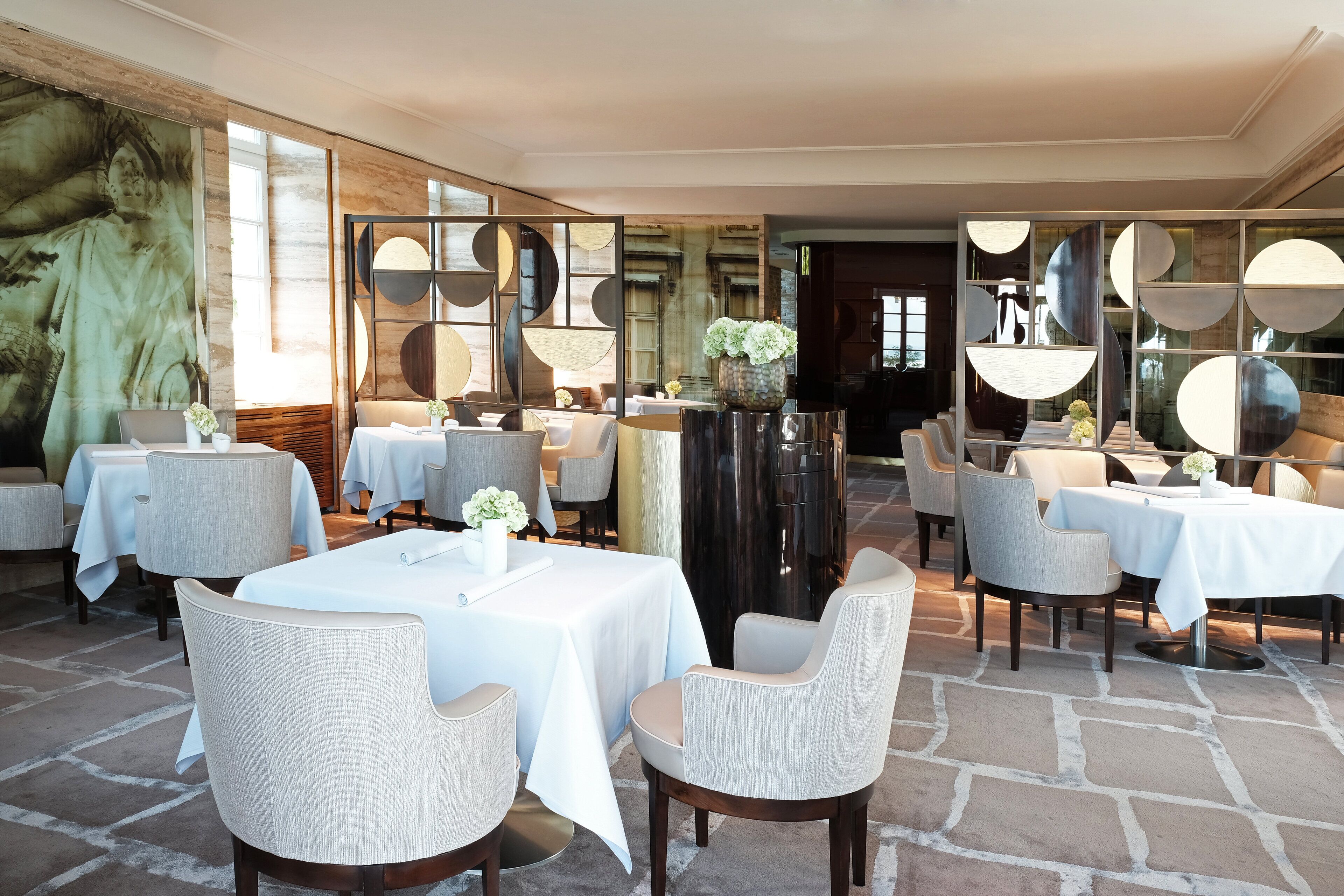 Ein Restaurant mit runden Tischen, Stühlen und einer großen Vase mit Blumen.