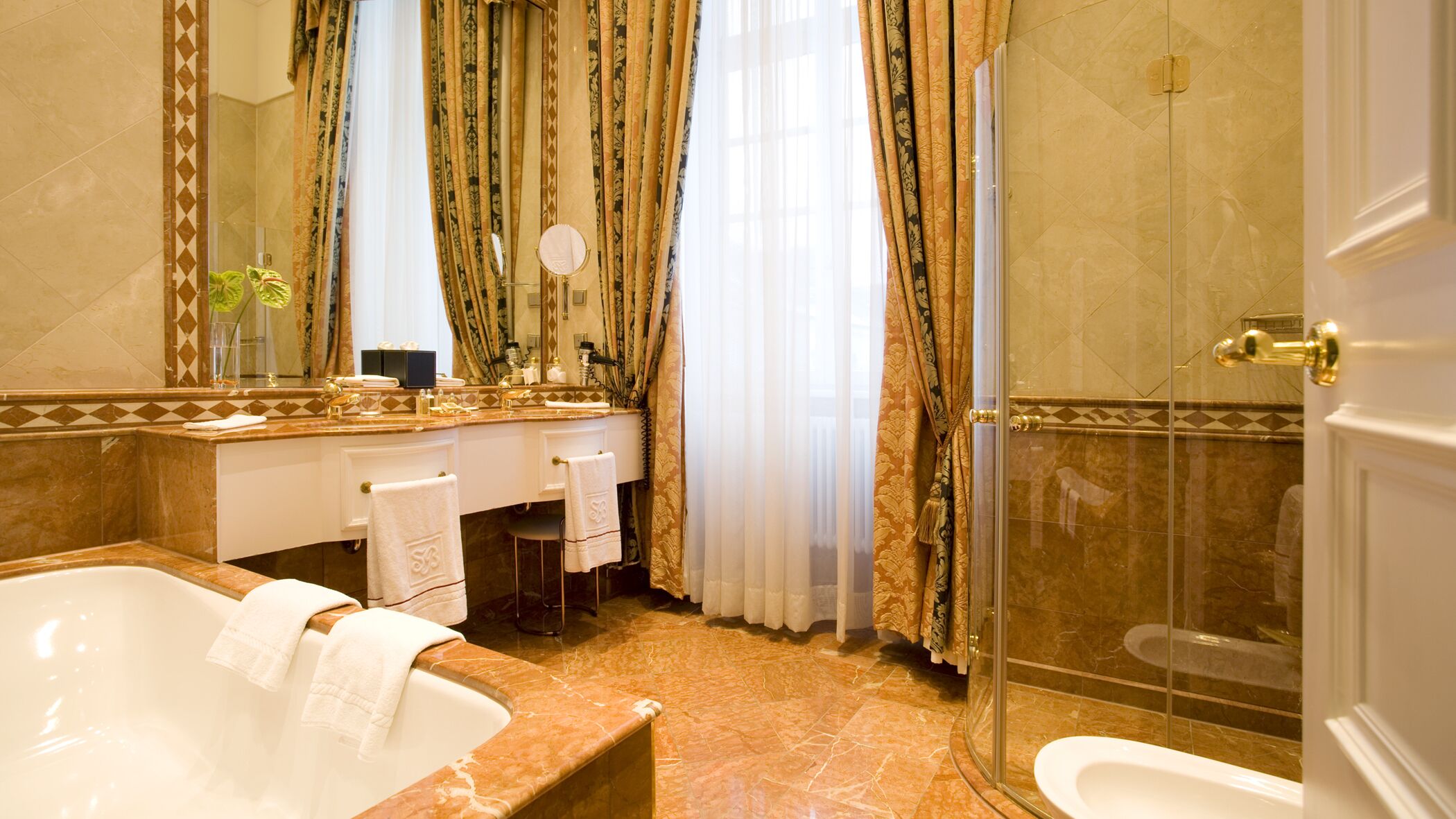 A luxurious bathroom with a large bathtub, a separate shower area, a vanity with a mirror, and a toilet.