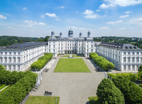 A large, symmetrical building with a central courtyard, surrounded by trees and featuring classical architecture.