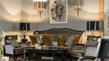 A modern living room with a sofa, armchairs, a coffee table, and wall-mounted lamps.
