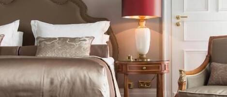 Una habitación de hotel con una cama grande, una mesita de noche con lámpara, una silla y un adorno en la pared.