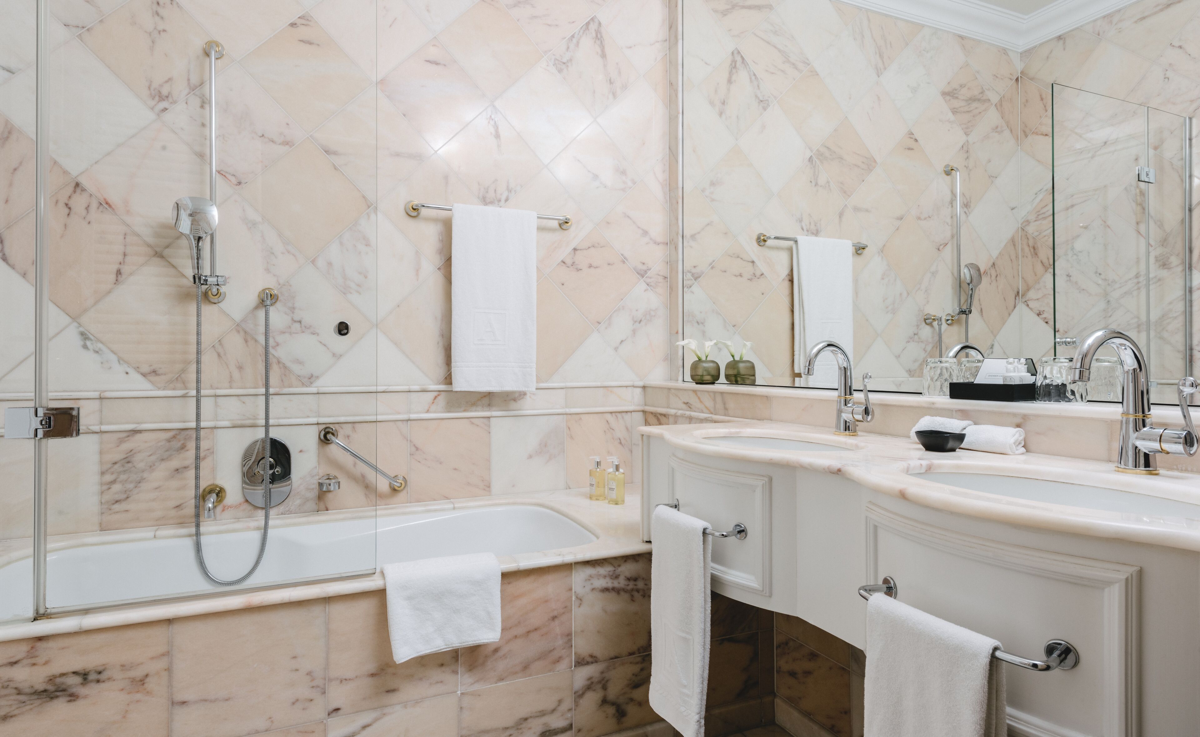A modern bathroom with a bathtub, two sinks, and a large mirror.