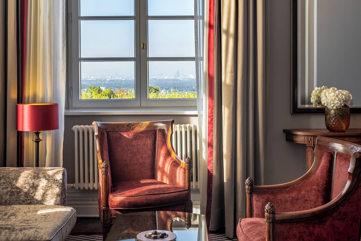 Una habitación con un ventanal grande, un sillón rojo, un sofá y una mesita de café.