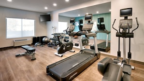 Ein Fitnessstudio mit Laufbändern, Crosstrainern und Gewichten.