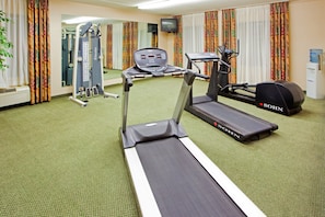 A hotel gym with a treadmill, stationary bike, and weight machines.