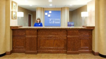 Un mostrador de recepción con diseño de madera, un letrero azul en la parte superior y el logotipo de 'Holiday Inn Express'.
