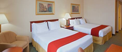 A hotel room with two beds, a chair, a desk, and two lamps.