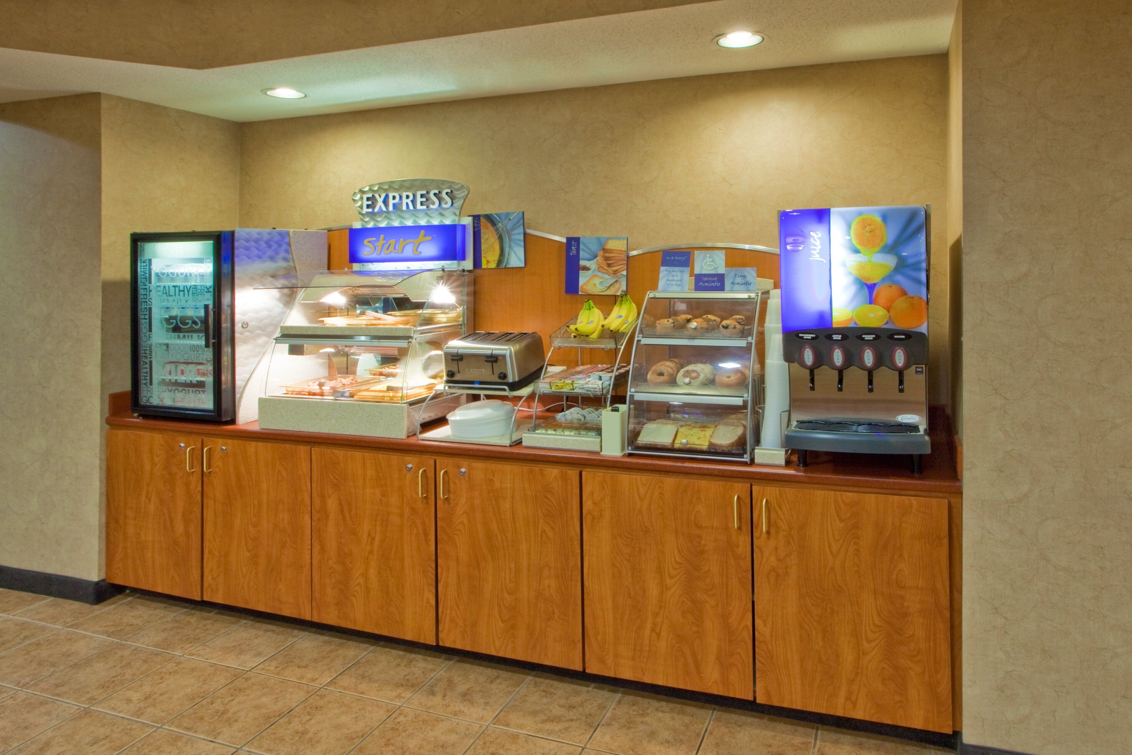 A breakfast bar with a juice dispenser, a yogurt display, and a toaster.