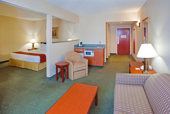 A hotel room with a bed, a sofa, a small table, a kitchenette, and a mirror. - Holiday Inn Express Hanover by IHG (Hanover)